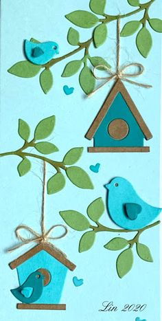 two blue birds sitting on top of a tree branch next to a birdhouse with green leaves