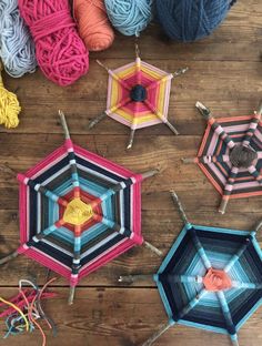 several crocheted umbrellas sitting on top of a wooden floor next to yarn