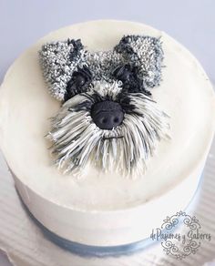 a cake decorated with a dog's face and hair on top of white frosting