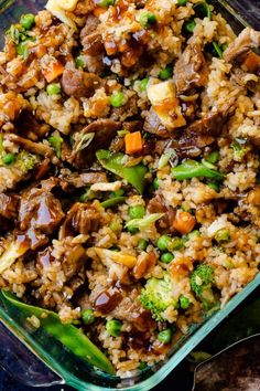 a casserole dish filled with rice, meat and veggies on a table