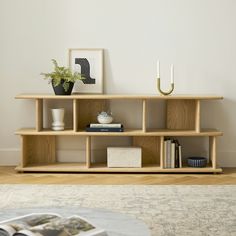 a living room with a book shelf and vases on top of the shelves next to a coffee table