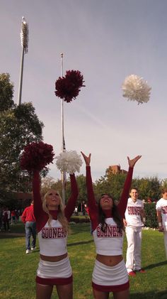 two cheerleaders in red and white outfits are throwing pom - poms