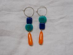 Handcrafted beads on 20mm surgical stainless steel hoops for sensitive ears, inspired by summer beach days in Victoria, Australia. Electric blue, blue-green translucent, and orange-yellow marbled drops in an asymmetrical style. Each pair is handcrafted and unique, these are a one-of-a-kind style and ready to ship. These are made from polymer clay for a surprisingly lightweight earring weighing around 3.5 grams each. Each bead has been hand formed, sanded, and buffed to a glossy high shine, with some translucent effect in the marbling. Wired with stainless steel, these earrings are a lightweight statement piece that will last a lifetime. Blue Hoop Earrings For Summer, Playful Blue Jewelry For Jewelry Making, Blue Hoop Earrings As Summer Gift, Blue Hoop Earrings For Summer Gift, Blue Hoop Earrings As A Summer Gift, Blue Resin Jewelry For Summer, Trendy Blue Round Bead Earrings, Everyday Blue Hoop Earrings, Playful Blue Nickel-free Jewelry