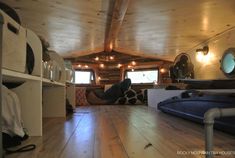 the inside of a tiny cabin with wood floors and walls, windows, and shelves