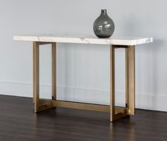 a vase sitting on top of a white marble table next to a wooden flooring