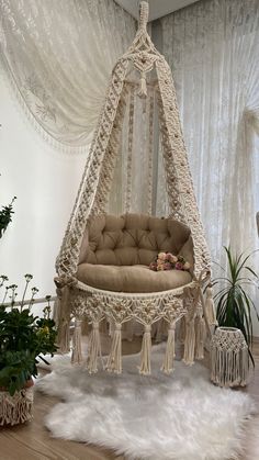 a white hammock hanging from the ceiling in a room with plants and rugs