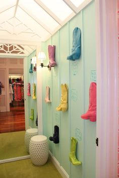 there are many boots hanging on the wall in this room, and one is wearing rain boots