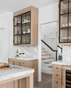 a kitchen with wooden cabinets and marble counter tops, white walls and wood flooring