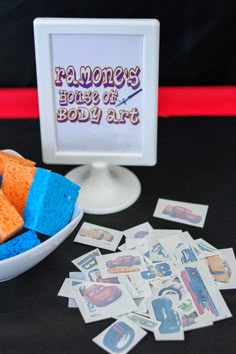 a bowl full of blue and orange sponges next to a plate with pictures on it