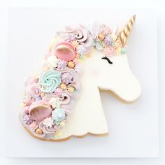 a decorated cookie shaped like a unicorn's head with pastel flowers on it