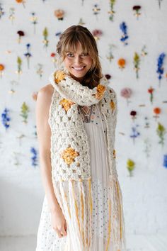 a woman wearing a white scarf with yellow flowers on it and smiling at the camera