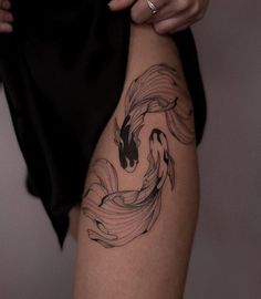 a woman's thigh with a koi fish tattoo on it