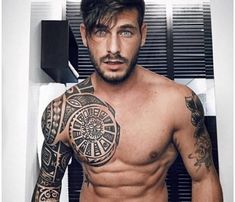 a shirtless man with tattoos on his arms and chest standing in front of a mirror