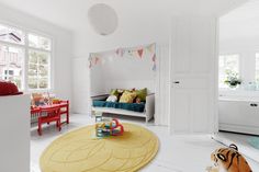 a child's room with white walls and flooring, including a yellow rug