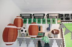 some paper lanterns are hanging on the wall above a shelf filled with soccer balls and other sports related items