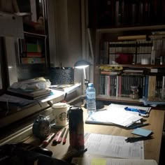 the desk is cluttered with papers and pens, bookshelves, and a lamp