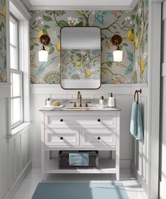 a bathroom with floral wallpaper and white vanity, blue rug and gold framed mirror