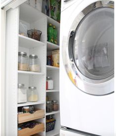 a white washer sitting inside of a dryer next to a shelf filled with items