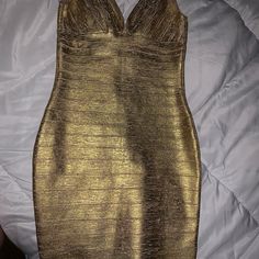 a gold dress is laying on a white bed and it's not too shiny