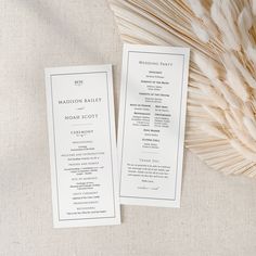 two wedding programs on top of each other next to some dried grass and a plant