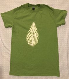 a green t - shirt with a white leaf on it