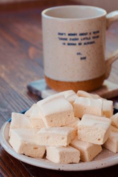 marshmallows on a plate next to a coffee mug