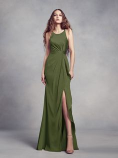 a woman in a long green dress posing for the camera with her legs slited