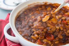 a person spooning beans into a white bowl on top of a red and white towel