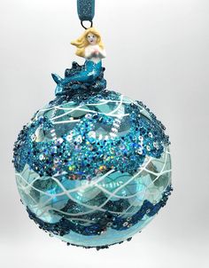 a glass ornament with a mermaid sitting on top of it