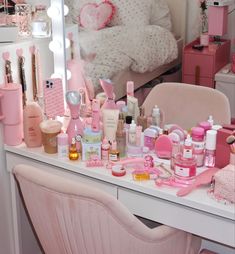 a pink vanity with lots of beauty products on it and a bed in the background