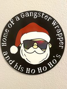 a santa clause sticker on the side of a white wall with words that read, home of a gangster wrapper and his ho ho hoo's