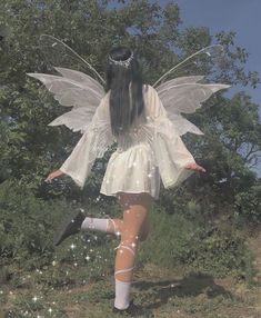 a woman dressed as a fairy standing in the grass