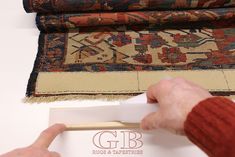 a person is holding a piece of paper in front of some rugs