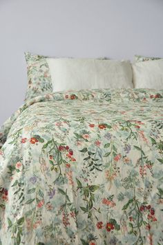 a bed with a floral comforter and two pillow cases on top of the headboard