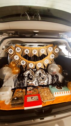 the trunk of a car is filled with various items and decorations for a birthday party