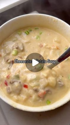 a white bowl filled with soup sitting on top of a stove next to a spoon