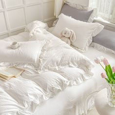 an unmade bed with white sheets, pillows and a stuffed animal on top of it