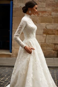 a woman in a white wedding dress is standing on the street with her hand on her hip