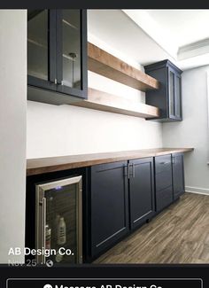 an empty kitchen with black cabinets and wood flooring