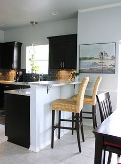 a kitchen with black cabinets, white counter tops and bar stools in the center