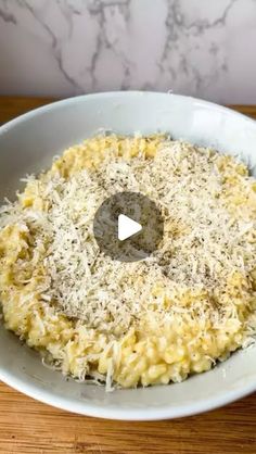 a bowl filled with pasta and parmesan cheese on top of a wooden table