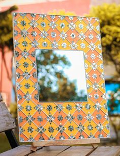 an orange and white frame sitting on top of a wooden table next to a mirror