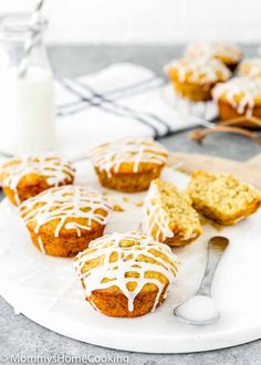 muffins with icing on a white plate next to a glass of milk