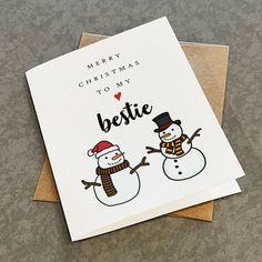 two snowmen are standing next to each other on top of a card that says merry christmas for my bestie