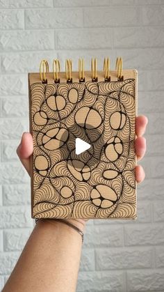 a person holding up a wooden notebook with spirals on it