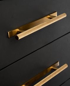 two brass handles on a black dresser