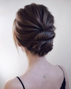 a woman with her back to the camera wearing a black top and braided hair