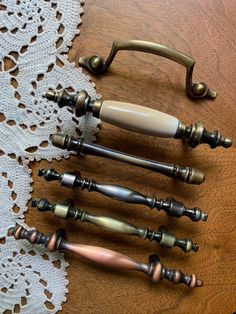 an assortment of knobs and handles on a wooden table with white lace doily