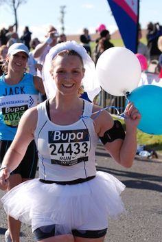 a woman is running in a race with balloons on her head and wearing a tutu