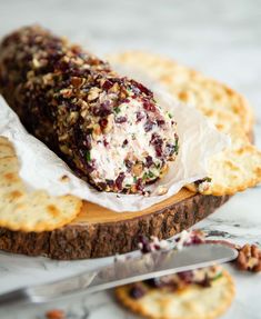 a cracker filled with fruit and nuts on top of a cutting board next to crackers